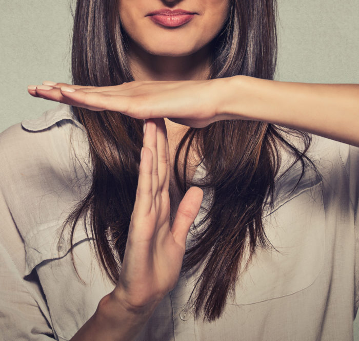 Closeup portrait, young, happy, smiling woman showing time out gesture with hands isolated on gray wall background. Positive human emotion facial expressions, feeling body language reaction, attitude